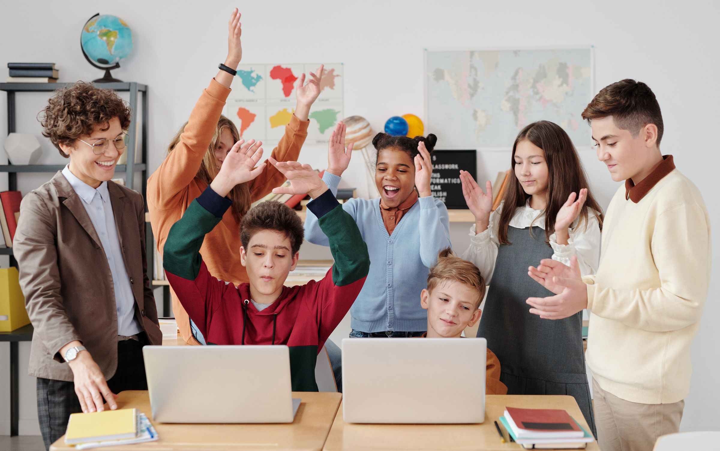 Estudiantes y profesor celebrando juntos una actividad en clase. Fotografía ilustrativa.